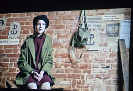 kadr z filmu - dziewczynka siedząca na ławce, w tle symbole powtania (photo)