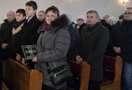 widok na członka rodziny trzymającego tabliczkę, w tle uczestnicy wydarzenia stoją w ławkach (photo)