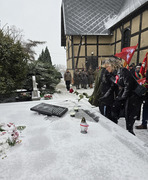 burmistrz Śmigla składająca różę na pomniku rozstrzelanych, w tle poczty sztandarowe oraz uczniowie z flagami (photo)